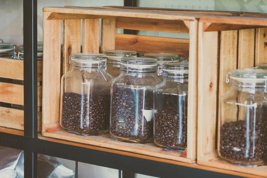 whole coffee beans stored in glass jars in crates